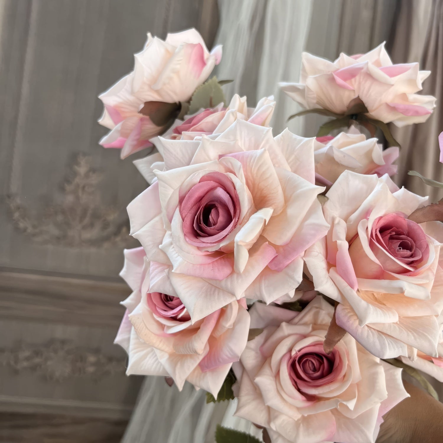 This image showcases a bouquet of artificial roses with a soft, elegant blend of creamy white petals and pink centers. The flowers have a highly realistic appearance with detailed textures and lifelike leaves.