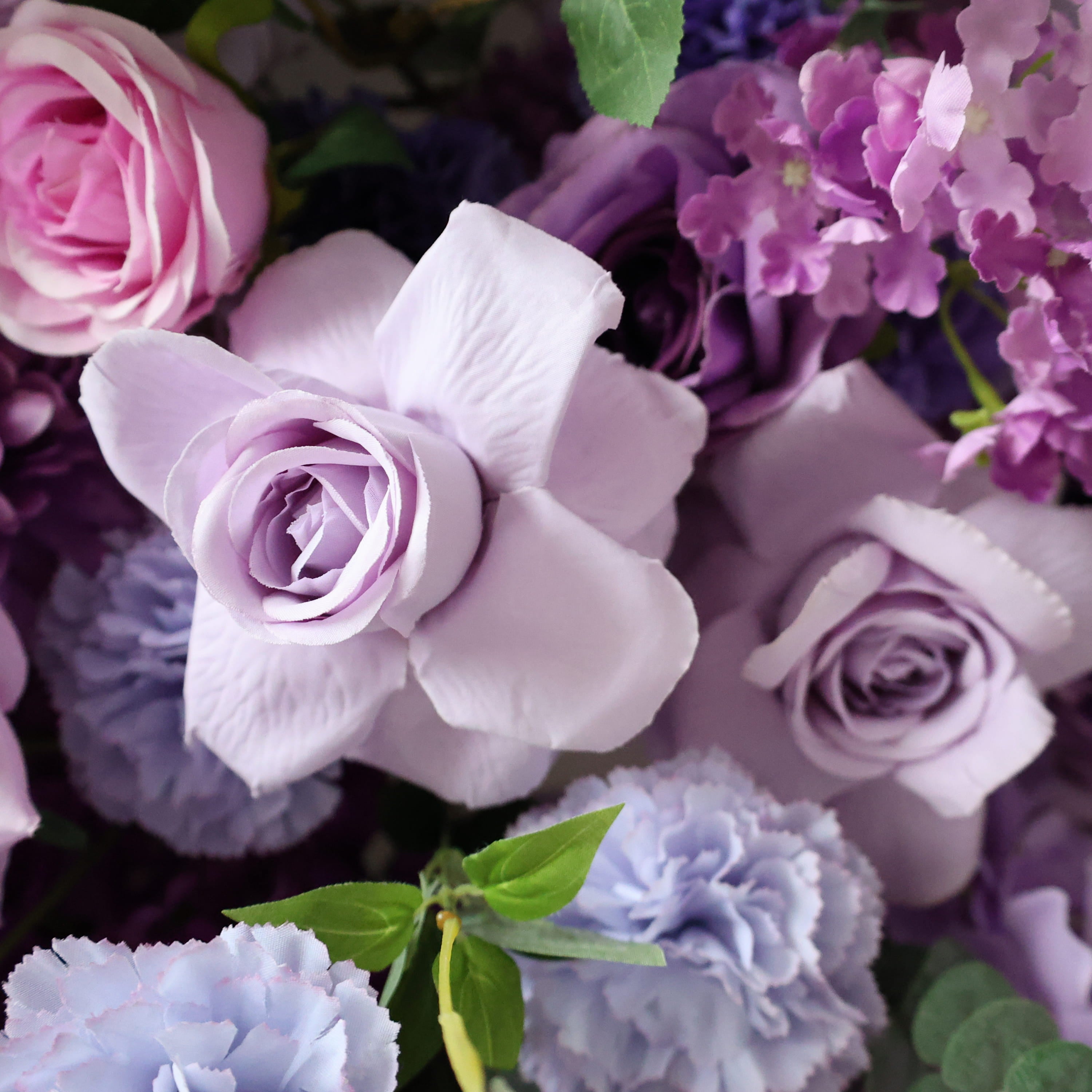 The ValarFlowers bouquet showcases a variety of blooms. It features light purple roses, pink roses, and lilac flowers. The petals are soft and the shapes are classic, ideal for floral arrangements.