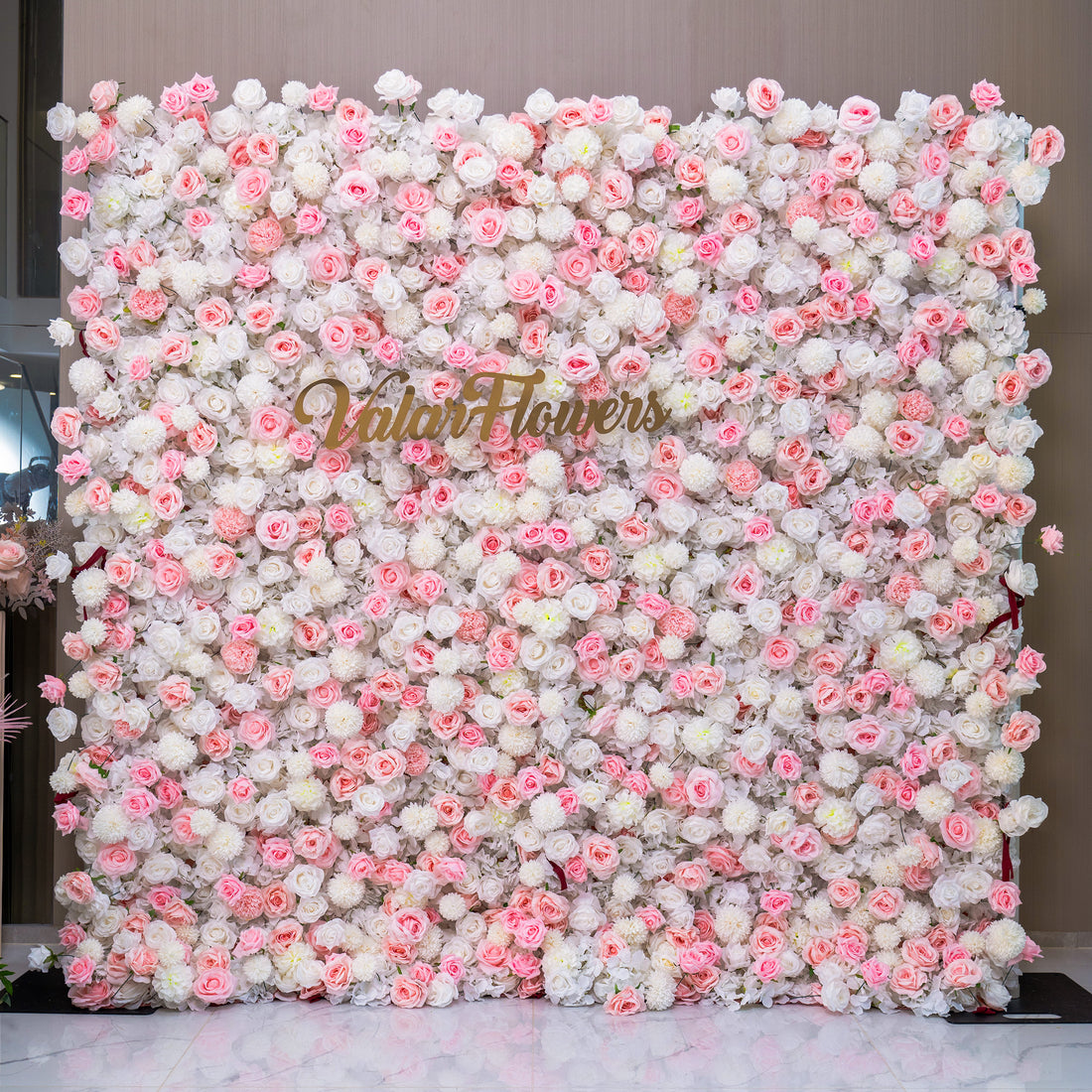 This image shows a beautiful floral wall with a mix of pink and white flowers. The wall is labeled &quot;Valar Flowers,&quot; making it a perfect backdrop for wedding decorations.