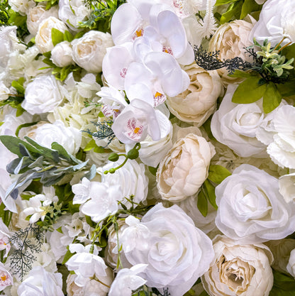 This close - up image focuses on the intricate details of the flower wall. It features a variety of white flowers, including orchids with visible red spots on their petals. The flowers are complemented by green leaves and other foliage, creating a lush and vibrant appearance. The close - up view allows for the appreciation of the delicate textures and natural - looking arrangements of the flowers.