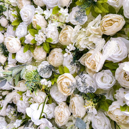 A close - up of the flower wall shows different types of white and off - white flowers with green leaves.