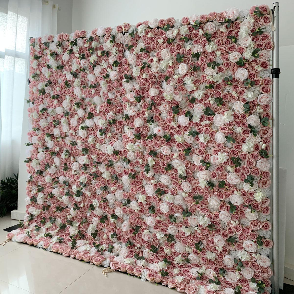 A wall with a pink background adorned with a variety of pink and purple flowers. The flowers have a soft, textured appearance, suggesting that they are made of fabric. The arrangement of the flowers on the wall creates an eye-catching display, adding a touch of elegance and sophistication to the space. It seems to be a decorative piece or installation, likely intended to create a calming and inviting atmosphere.