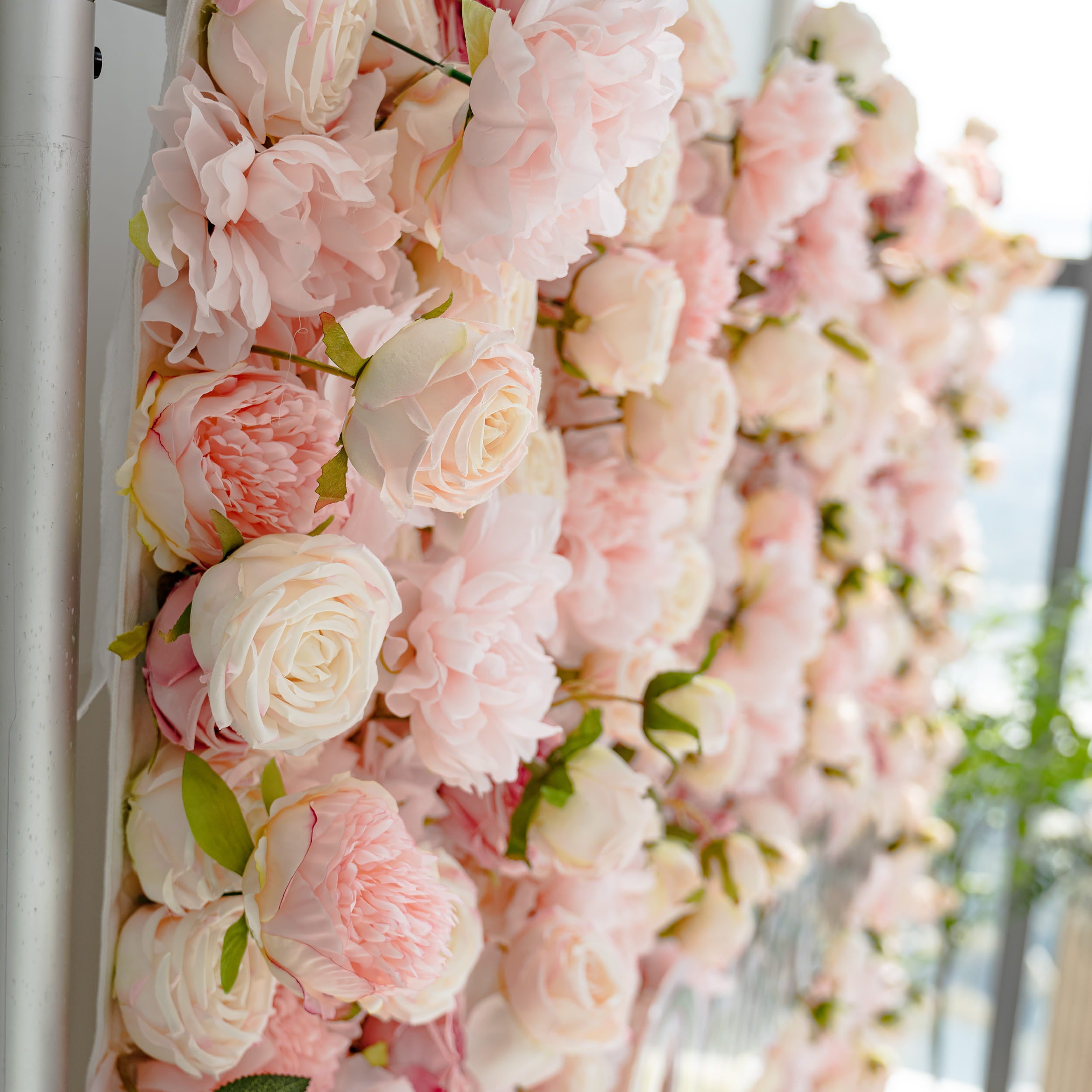 The image showcases a stunning display of artificial flowers. Each flower has intricately designed petals with soft pink and white hues. The realistic leaves and dense arrangement highlight the detailed craftsmanship.