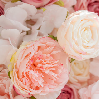 A close - up of two types of flowers: a pink peony with soft petals and a creamy - white rose. They are part of a larger arrangement of pastel - colored blooms.
