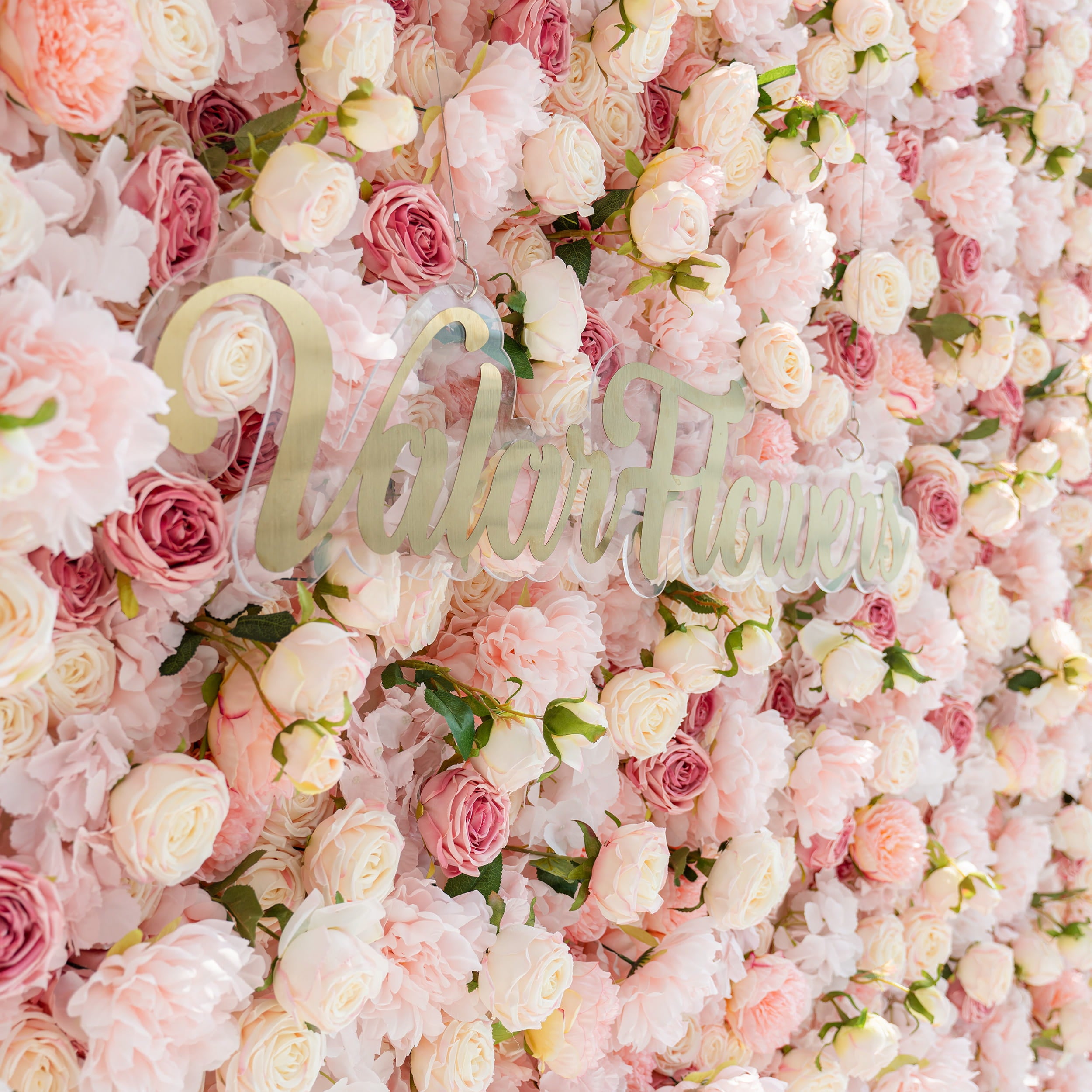 A stunning flower wall adorned with an array of pink and white roses. The text &quot;Valar Flowers&quot; is prominently displayed, adding a touch of elegance and branding to the beautiful floral backdrop.