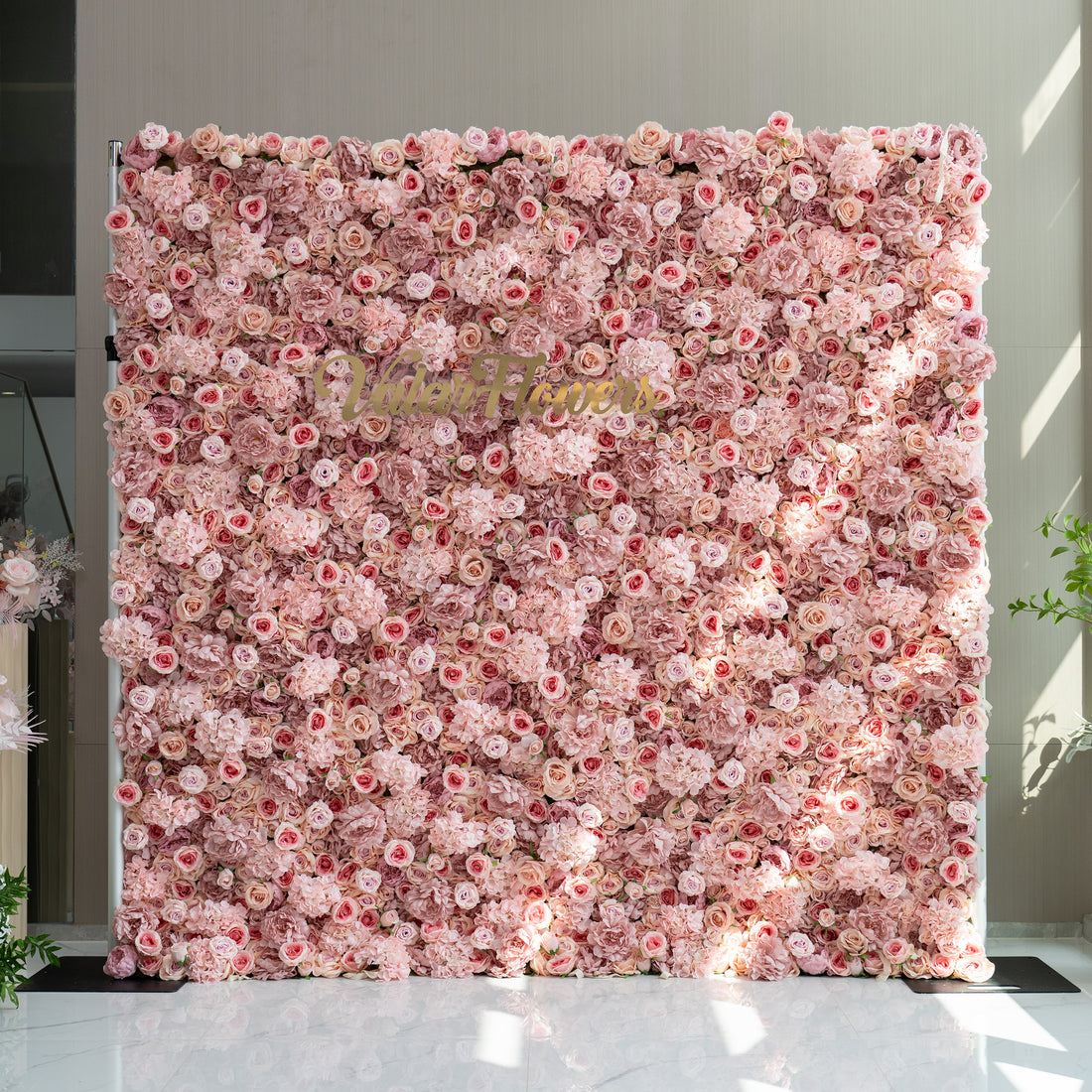 This image features a stunning floral wall adorned with a plethora of light pink and rose - colored flowers. In the center of the wall, the brand name &quot;ValarFlowers&quot; is displayed in elegant gold lettering. The overall ambiance is soft, romantic, and inviting, making it ideal for events such as weddings, bridal showers, or romantic celebrations.