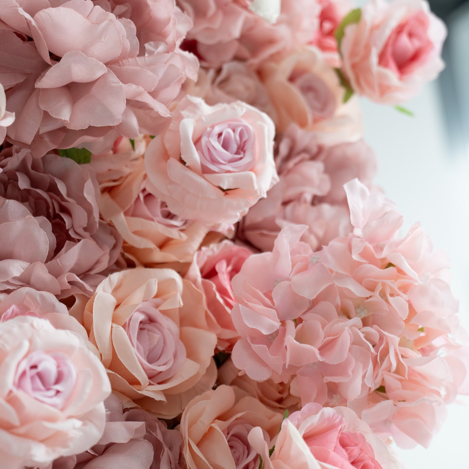 This image showcases a close - up of a floral wall. The wall is densely packed with large, soft - pink roses, creating a romantic and elegant appearance. The petals are intricately layered, and the overall color scheme is a delicate blend of pastel pinks. This type of floral wall is often used for decorative purposes in events like weddings, parties, or photo shoots.