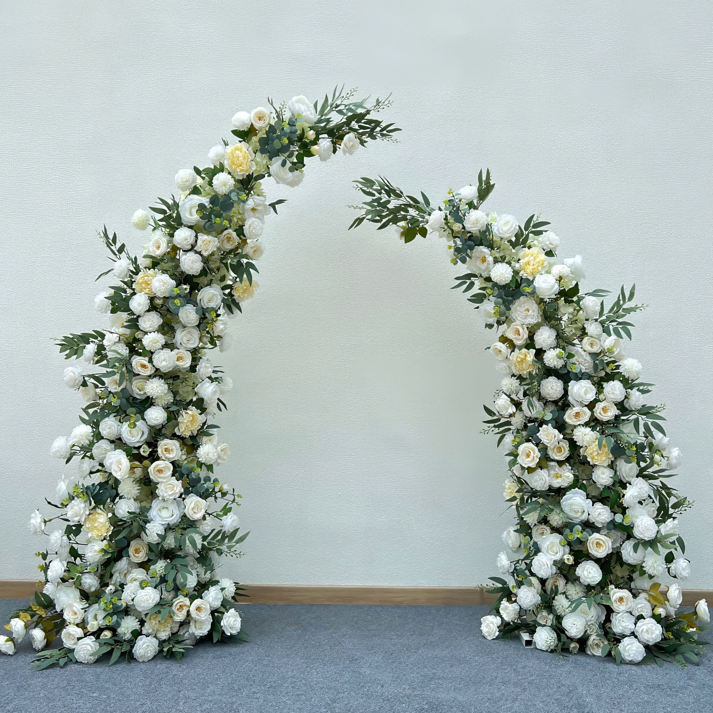 Stunning artificial floral arch for weddings, ceremonies, and special events. Features white and cream flowers (roses, peonies, hydrangeas) with lush greenery, arranged in a cascading effect on a sturdy frame. Ideal for indoor/outdoor use. Elegant, timeless design.