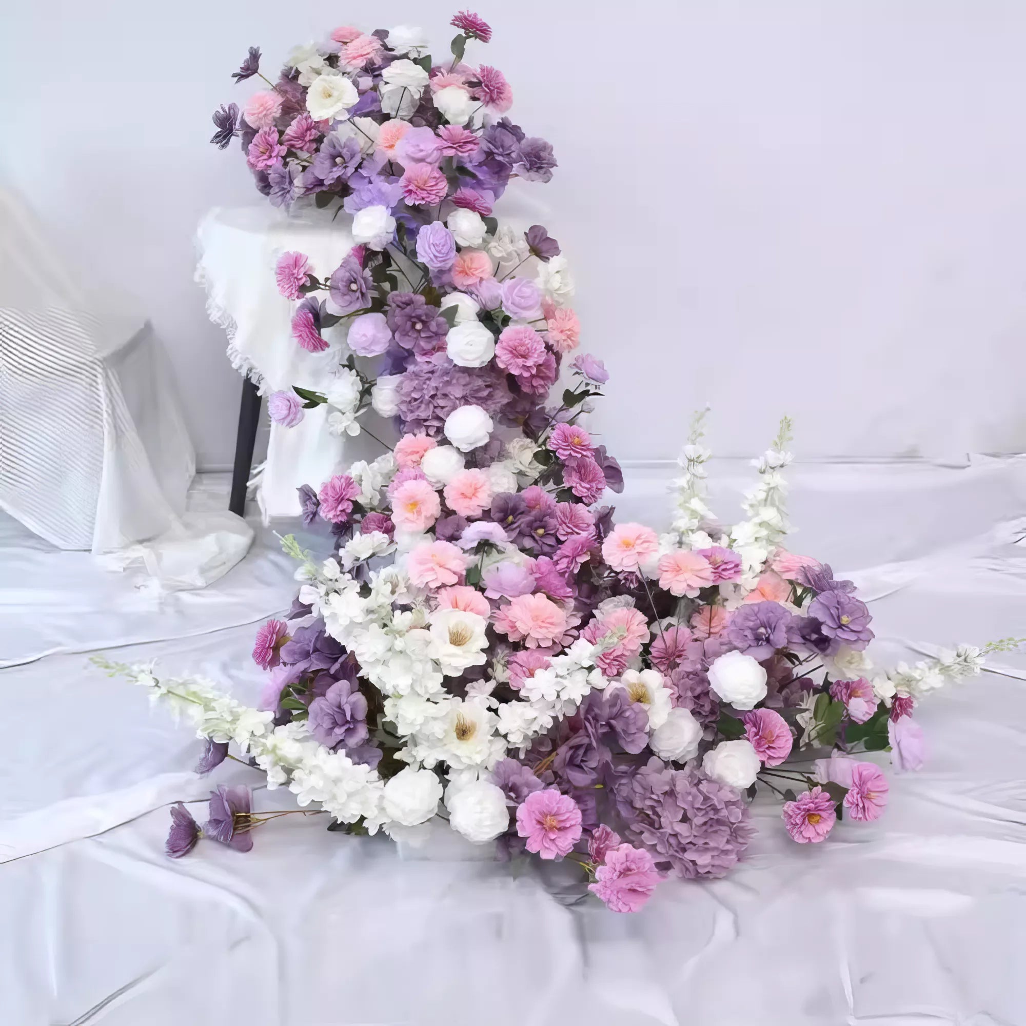 Elegant floral table runner featuring cascading purple, pink, and white blooms. Perfect for weddings or special occasions, adding a romantic touch with its soft pastel palette and lush arrangement, enhancing the beauty of any sophisticated setting.