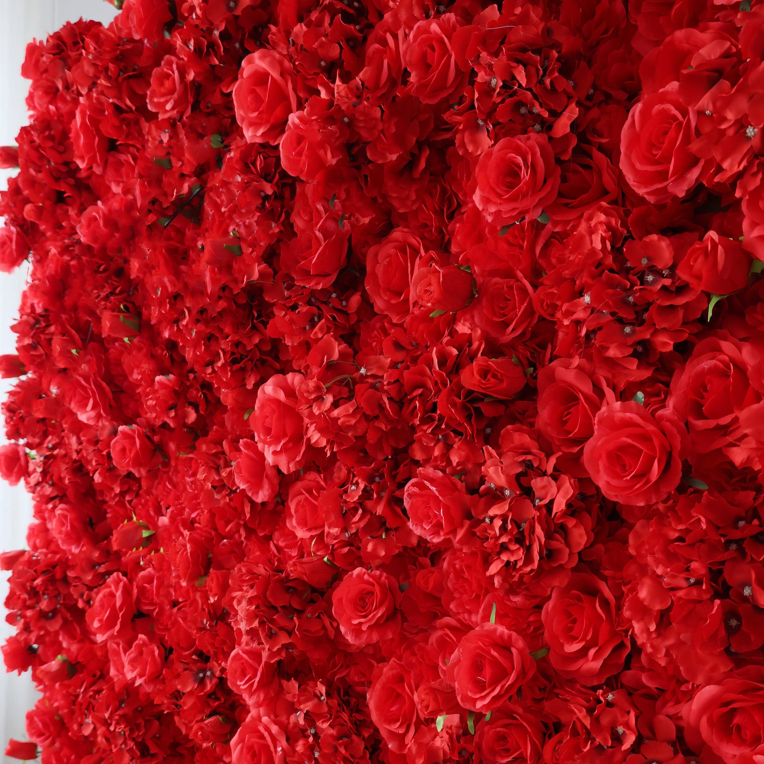 A vibrant side-angle view of the ValarFlowers red flower wall, showcasing densely packed silk roses and hydrangeas with intricate details, creating a luxurious and romantic backdrop for any event.