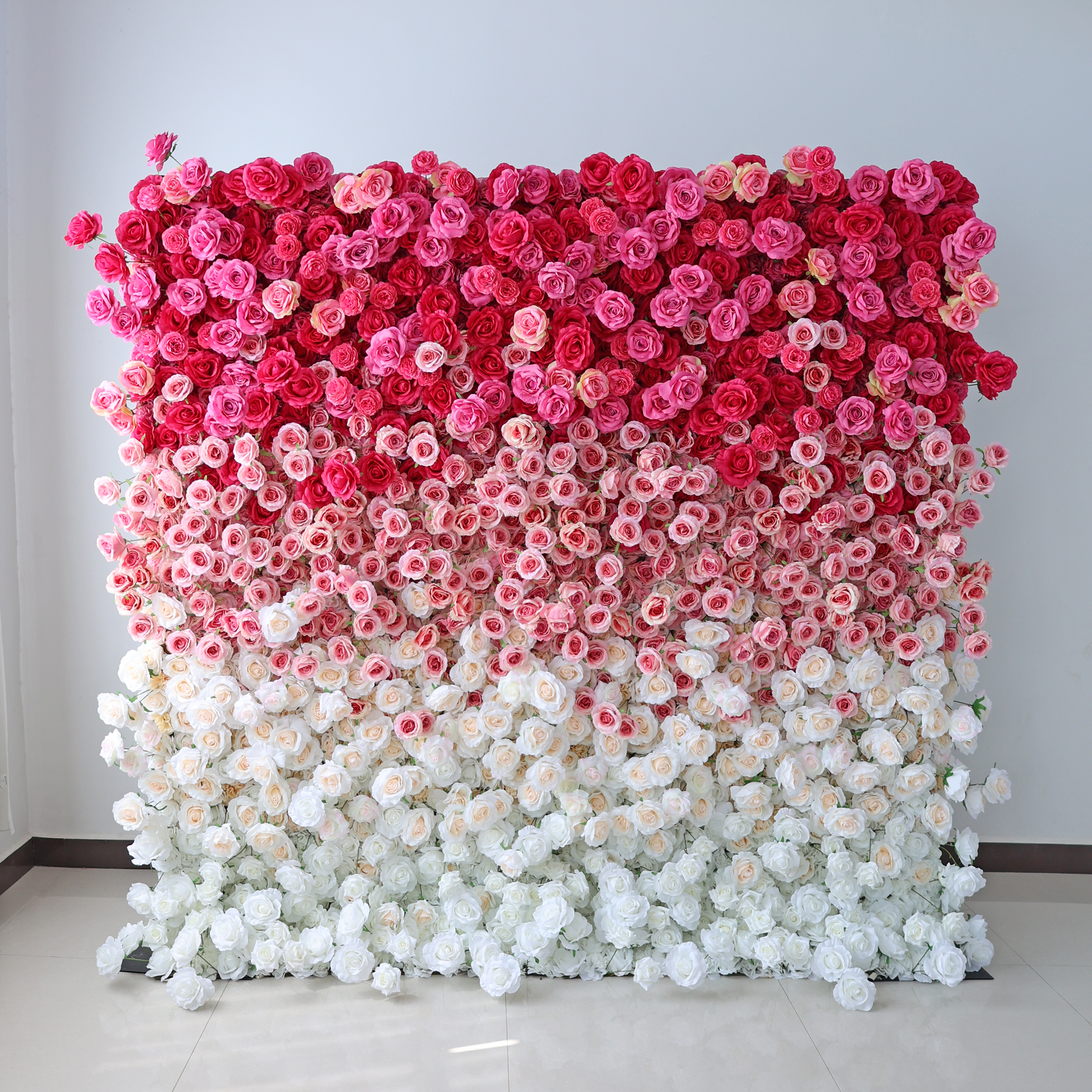 This artificial flower wall is a stunning decor option. It features a gradient of pink to white roses, is easy to install, customizable in size, durable, and suitable for various events like weddings and parties.